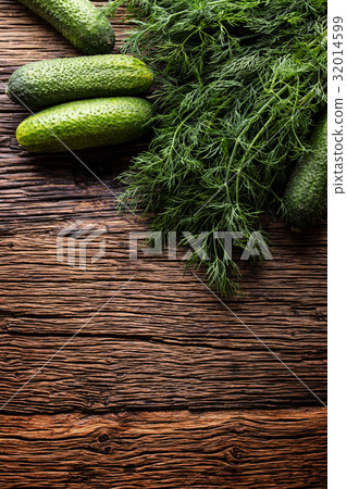 Cucumber and dill on very old rustic oak table. 32014599