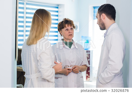 Mature doctor discussing with nurses in a hallway 32026876