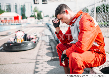 Karting racer sits on a tire, outdoor kart track Karting racer sits on a tire, outdoor kart track 32026902