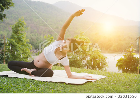 asian pregnant woman practicing yoga on green grass in public park. concept of prenatal exercise, maternity, fitness, healthy lifestyle and relaxation. 32031556