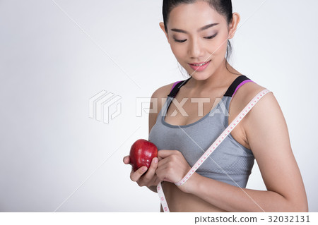 sporty fitness woman with measuring tape and red apple standing against white background. diet, sport and health concept 32032131