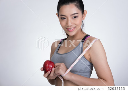 sporty fitness woman with measuring tape and red apple standing against white background. diet, sport and health concept 32032133