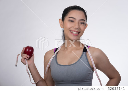 sporty fitness woman with measuring tape and red apple standing against white background. diet, sport and health concept sporty fitness woman with measuring tape and red apple standing against white background. diet, sport and health concept 32032141