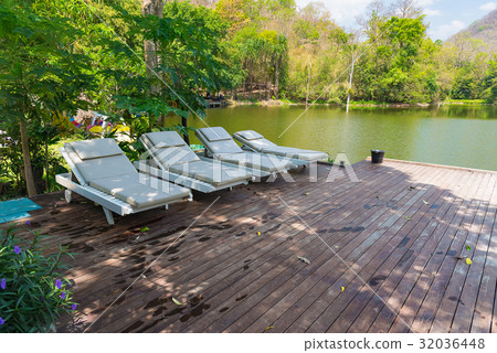 Wooden deck chairs on wood flooring near lake Wooden deck chairs on wood flooring near lake 32036448