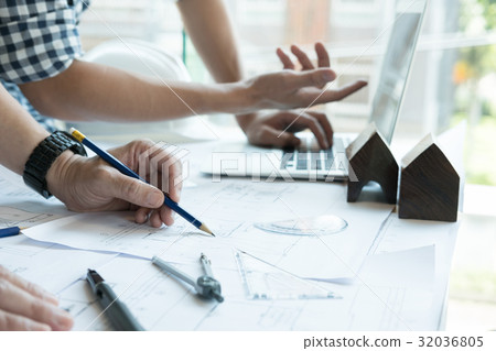 Architect working on real estate project with partner at workplace. Male engineer hand discussing with colleague on living house blueprint at office. Business, people, construction and building concept Architect working on real estate project with partner at workplace. Male engineer hand discussing with colleague on living house blueprint at office. Business, people, construction and building concept 32036805