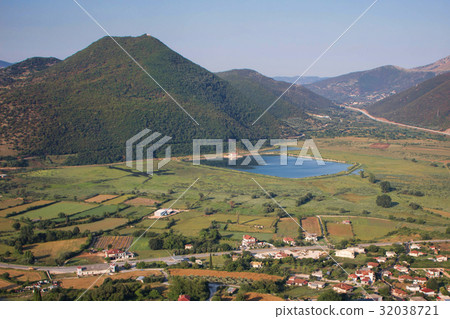 View on people's houses, artificial lake and green mountains at sunset 32038721
