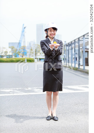 A woman in a suit wearing a helmet by placing the building's house in his palm 32042504