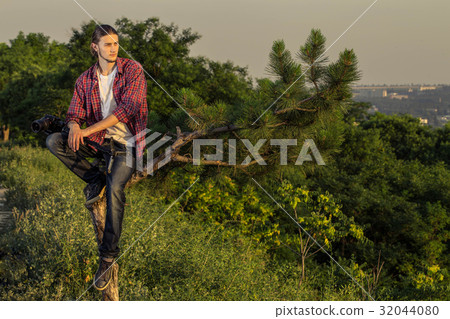 Young photographer sitting on the tree. 32044080