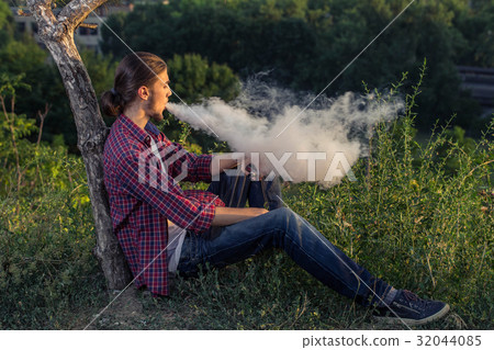 Handsome young man smoking electronic cigarette. 32044085