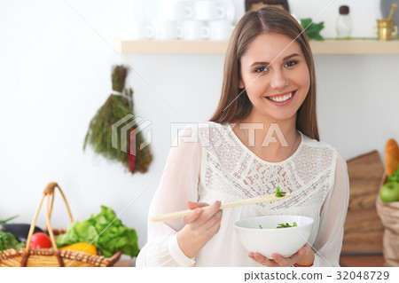 Young happy woman is cooking or eating fresh salad 32048729