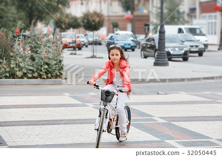 Cute kid girl in blue helmet going to ride her 32050445
