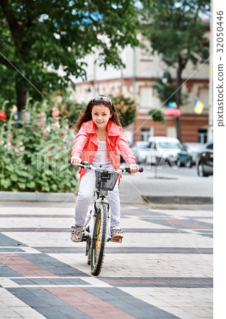 Cute kid girl in blue helmet going to ride her 32050446