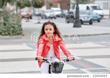 Cute kid girl in blue helmet going to ride her 32050447