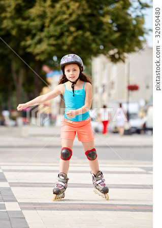 Cute little girl learning to roller skate outdoors Cute little girl learning to roller skate outdoors 32050480