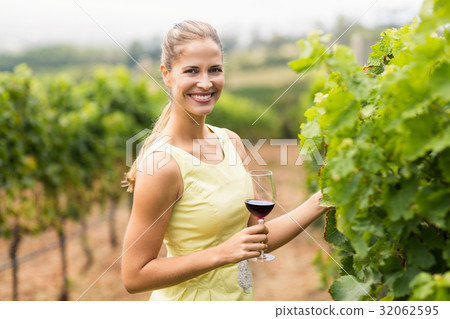 Portrait of female vintner holding wine glass and inspecting grape crop Portrait of female vintner holding wine glass and inspecting grape crop 32062595