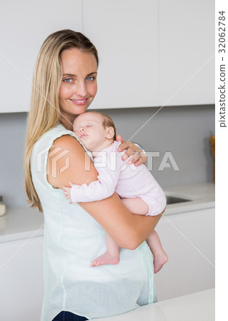 Mother carrying her baby in kitchen at home 32062784
