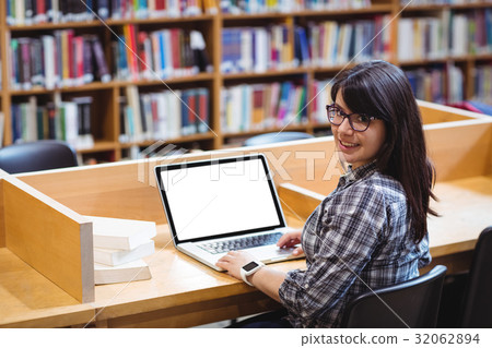 Smiling Female student using laptop in library 32062894