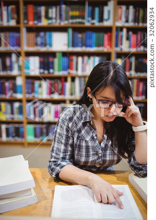 Female student reading book in library 32062934