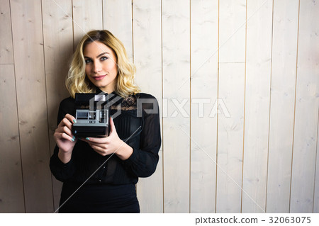 Woman holding a camera against textured background 32063075
