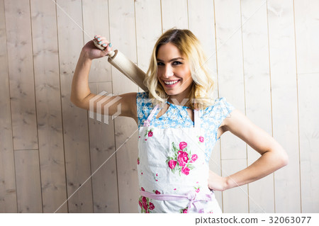 Woman in apron holding a rolling pin against texture background 32063077