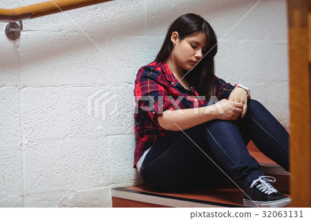 Upset female student sitting on staircase Upset female student sitting on staircase 32063131