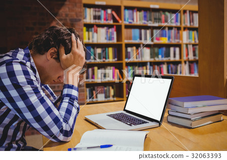 Depressed student sitting in library with laptop Depressed student sitting in library with laptop 32063393