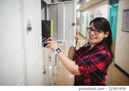 Female student keeping her book in the locker 32063406