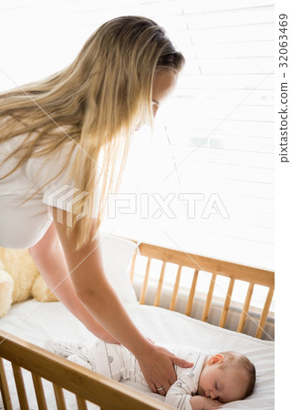 Mom putting baby to sleep in baby bed Mom putting baby to sleep in baby bed 32063469