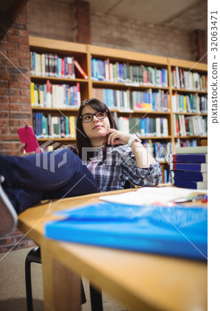 Female student sitting in library with mobile phone Female student sitting in library with mobile phone 32063471