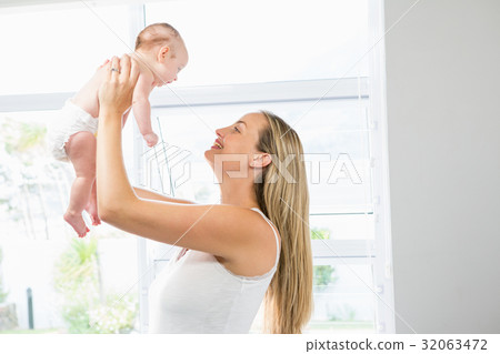 Mother playing with her baby in living room 32063472