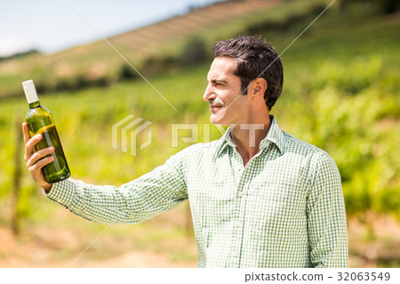 Smiling vintner looking at bottle of wine Smiling vintner looking at bottle of wine 32063549