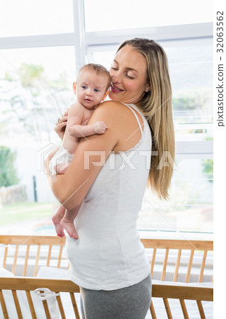 Mother carrying her baby in living room 32063562