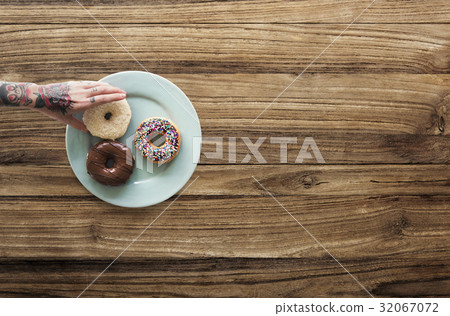 Hand with tattoo reaching for donut Hand with tattoo reaching for donut 32067072