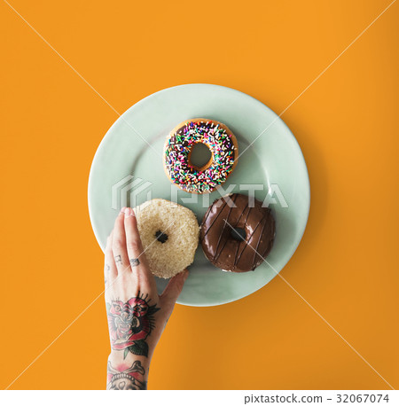 Hand with tattoo reaching for donut Hand with tattoo reaching for donut 32067074
