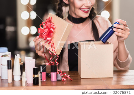 Happy girl opening present box with cosmetics Happy girl opening present box with cosmetics 32076871