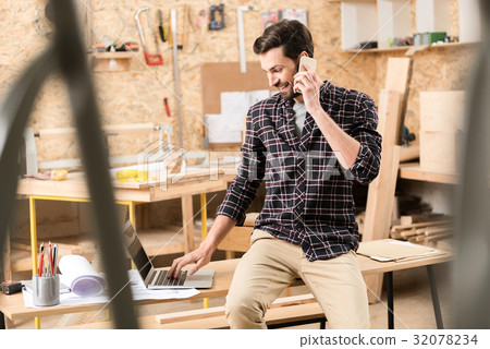 Pleasant cheerful carpenter it typing on notebook Pleasant cheerful carpenter it typing on notebook 32078234