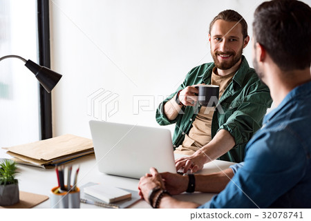 Merry smiling worker sitting in office Merry smiling worker sitting in office 32078741