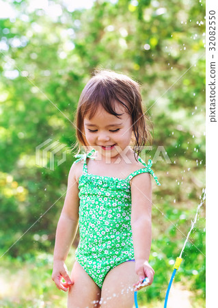 Happy toddler girl playing with sprinkler Happy toddler girl playing with sprinkler 32082550