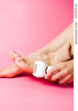 Female scrubbing hard skin from feet 32085535