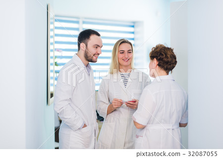 Mature doctor discussing with nurses in a hallway Mature doctor discussing with nurses in a hallway 32087055