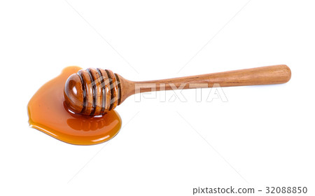 Honey dripping from a wooden honey dipper 32088850