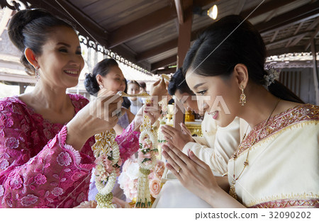 Two happy women are giving garlands to bride and groom for congratulations 32090202