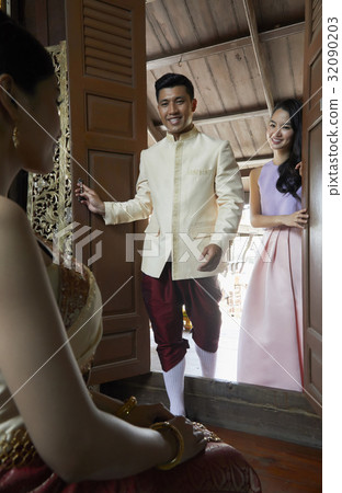 The groom and a bridesmaid are looking at the bride and smiling. 32090203