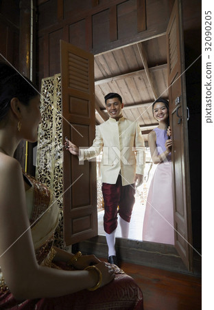 The groom and a woman are opening the door and smiling with the bride who sits in the room  32090205