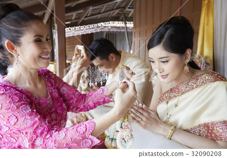 Someone is preparing to put garland on the neck of both groom and bride. 32090208