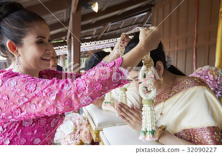 An elder is placing garland on the neck of bride. 32090227