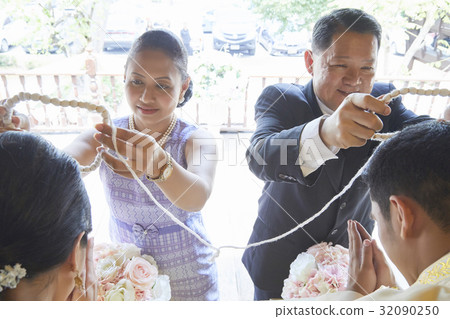 Groom and bride are being given chains by their parents at wedding ceremony 32090250