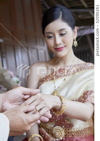 A bride is given a ring at her wedding ceremony. 32090261