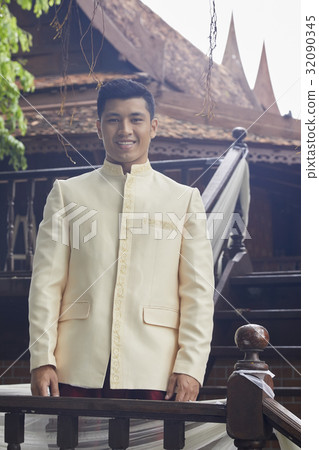 Handsome man wearing traditional wedding clothes is standing at the balcony 32090345