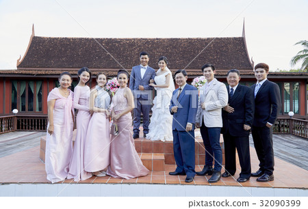 happy newlyweds and their family are standing, smiling and posing 32090399